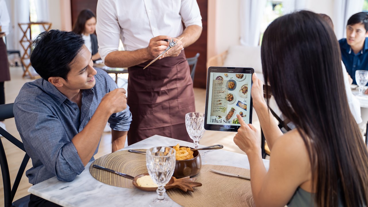 Diners using a tablet menu at a restaurant table